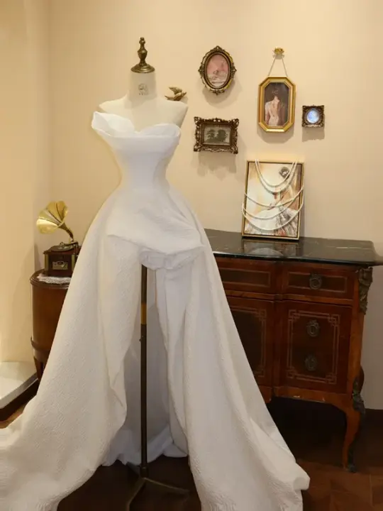 White strapless, fitted, long ball gown with an asymmetrical hem; bridal gown R7175