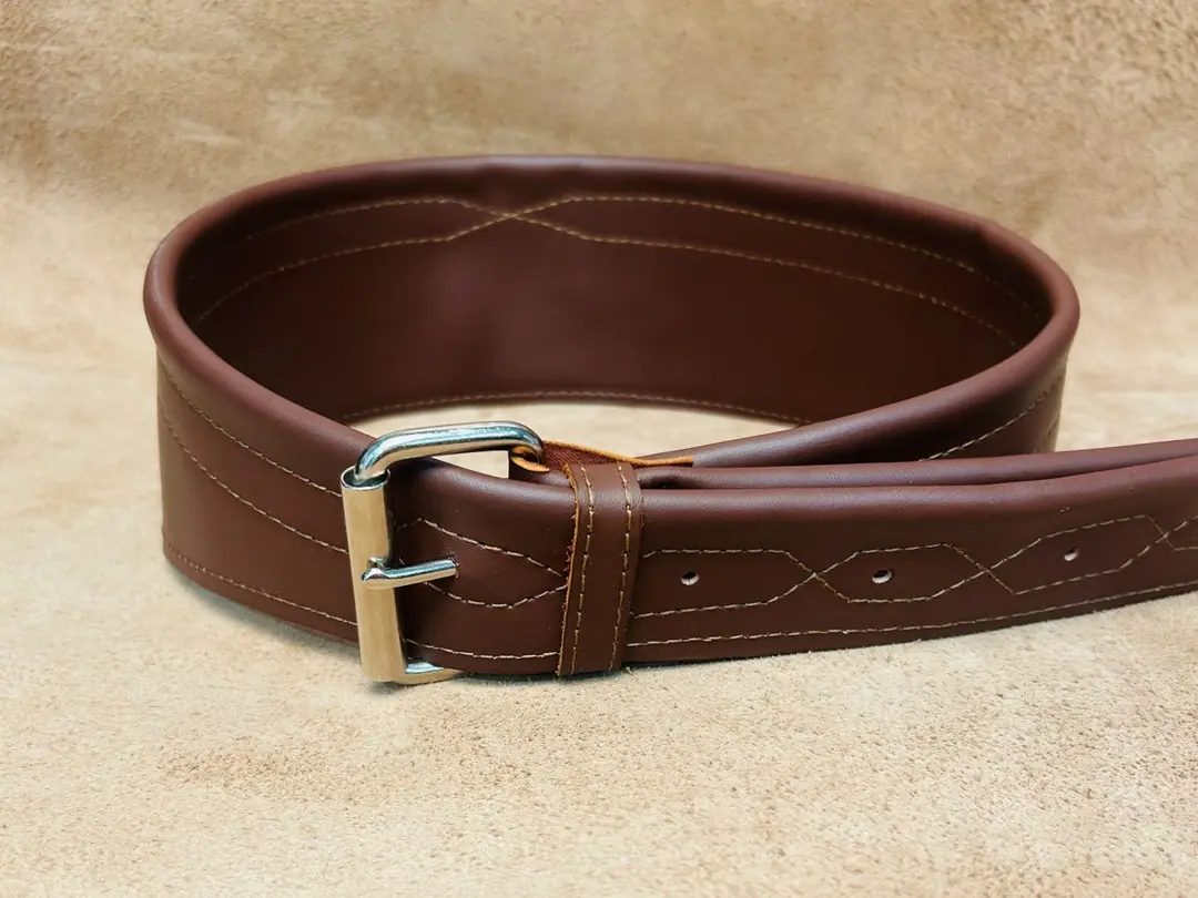 Guitar strap in leather color Cinnamon, rolled up on its side. The strap bas a large plain silver buckle